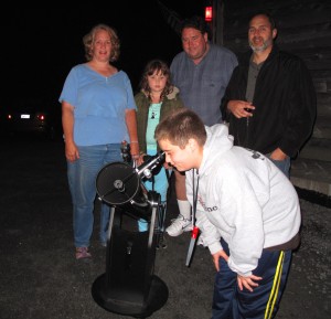 A group of people standing in front of a telescope.