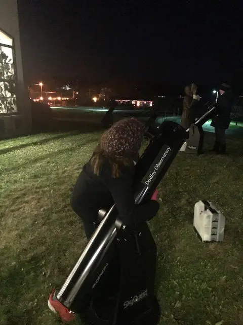 A woman looking through a telescope at night.
