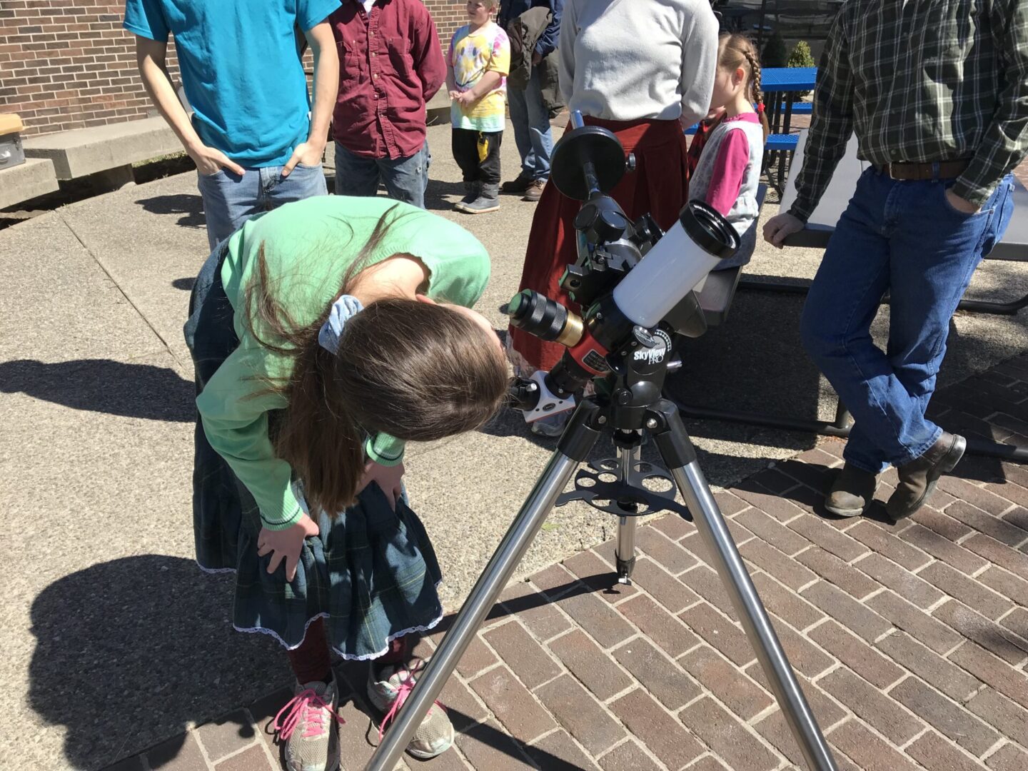 A group of people at Astro Labs, gazing through a telescope.