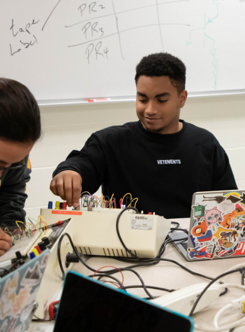 A group of people working on electronics in a classroom.
