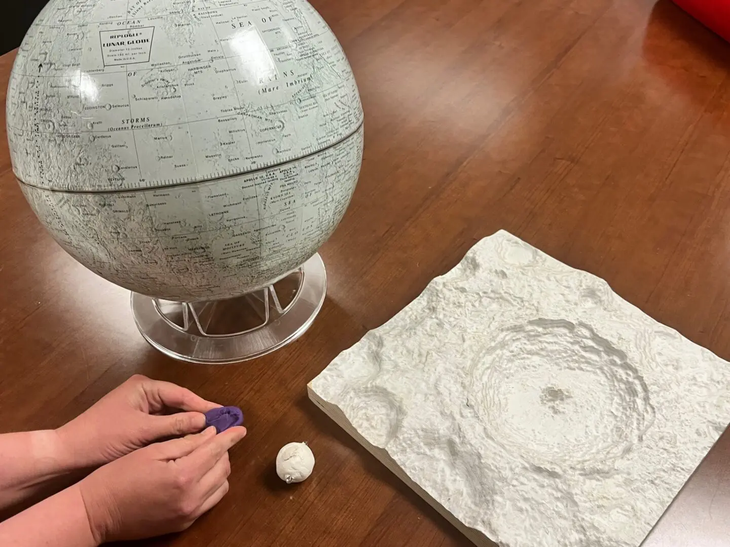 A child is making a model of a planet on a table.