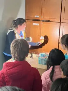 Teacher showing children colorful chalk sticks.